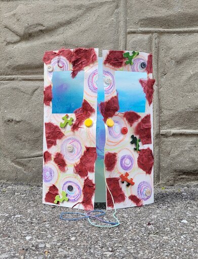 An embellished and painted card folded to look like a door opening